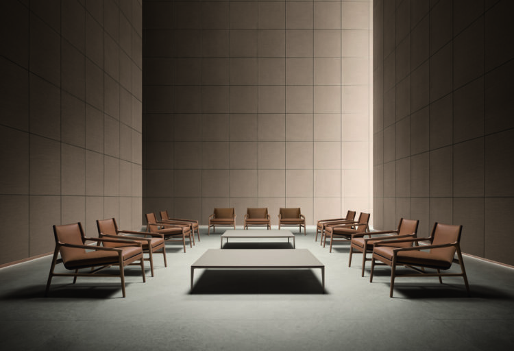 Rimadesio Ascot lounge armchairs in brown leather arranged around two low tables in a tall paneled room.