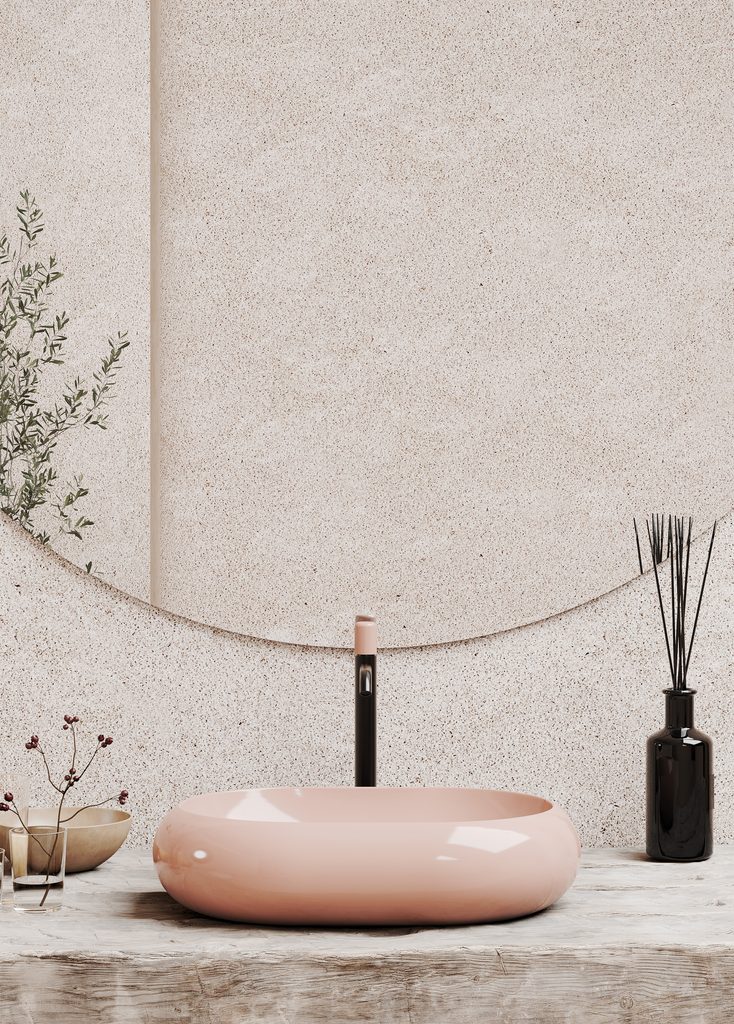 Hastings Petra 60 blush pink vessel basin with rounded edges on a wood vanity beneath a circular mirror.
